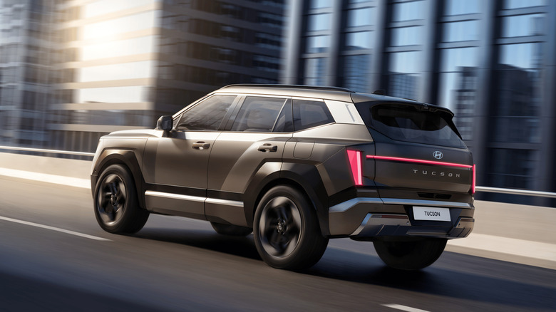 2027 Hyundai Tuscon driving along urban highway, rear-left 3/4 view