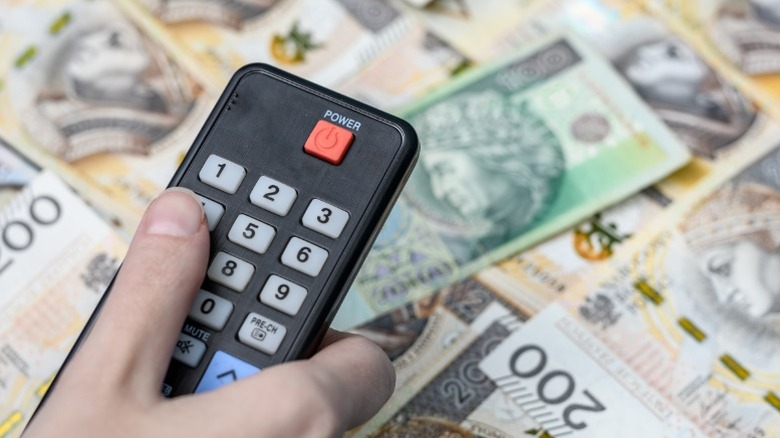 A television remote on top of a pile of money