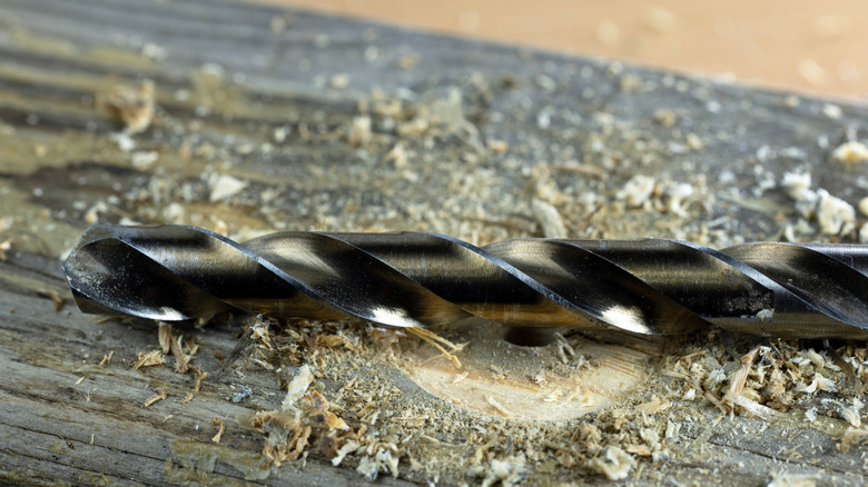An image of a drill bit resting on a piece of wood