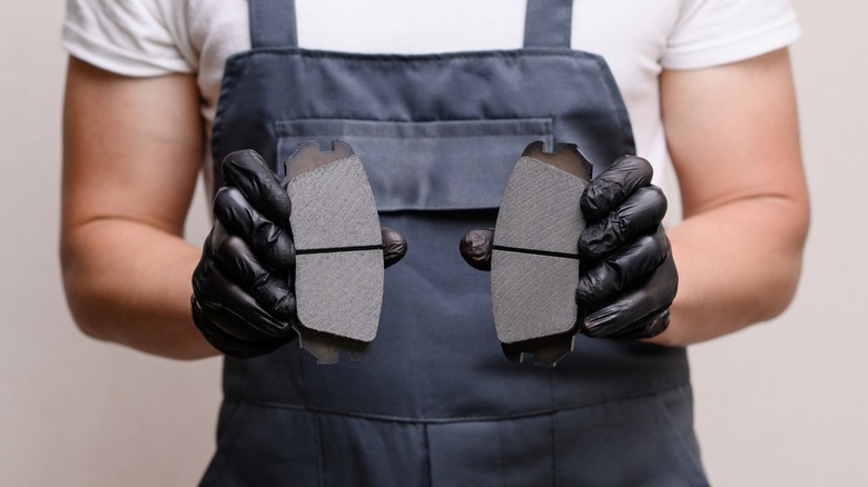 A person holding two new car brake pads