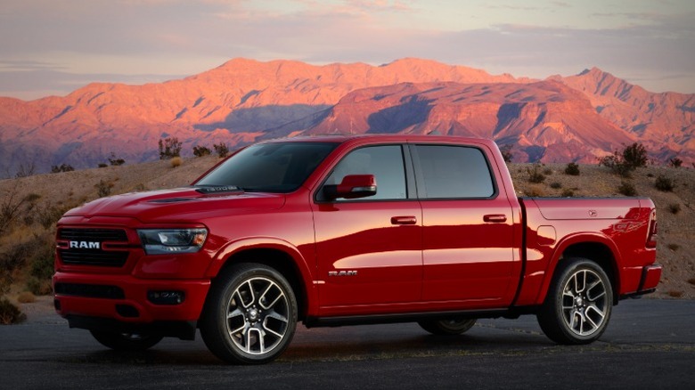 Red 2024 Ram 1500 Laramie GT parked on a desert road at sunset with mountains in the distance