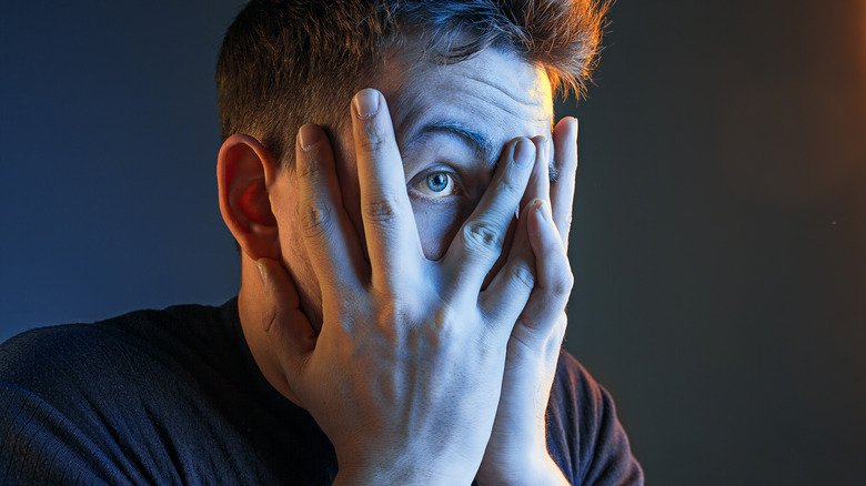 Man peeking through fingers