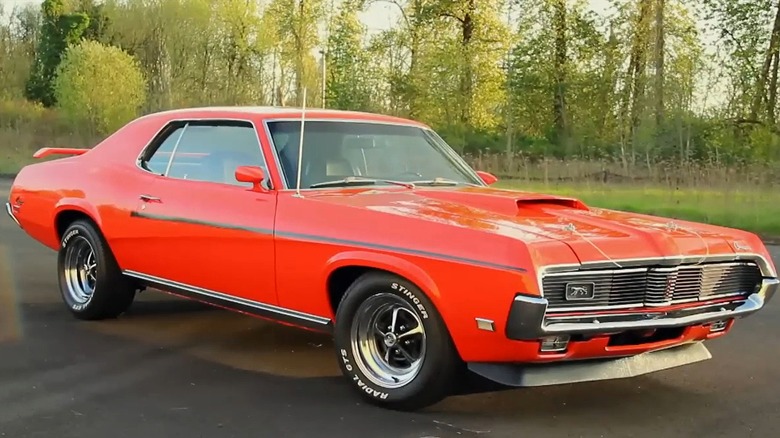 A bright red 1969 Mercury Cougar Eliminator, trees in the background.
