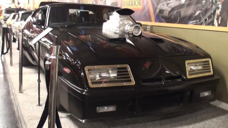 The iconic black Interceptor from Mad Max sitting behind a rope barrier.