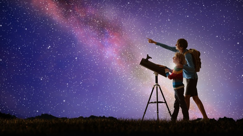 adult and child looking at space with telescope