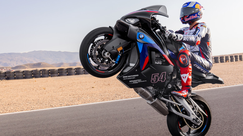 Side profile view of a rider on a 2024 BMW S 1000 RR doing a wheelie