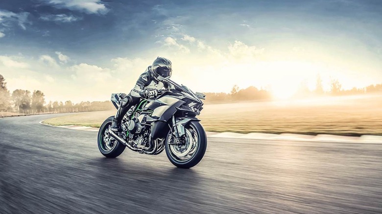 Kawasaki's supercharged H2R motorcycle riding on a racetrack at sunset