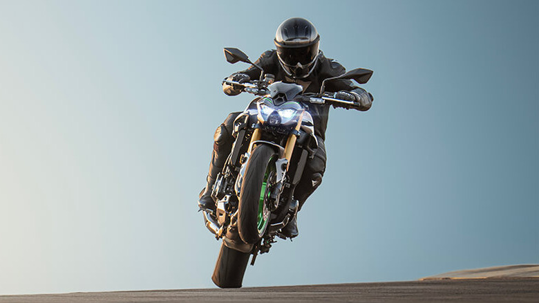 Kawasaki Z900 popping a wheelie on a racetrack