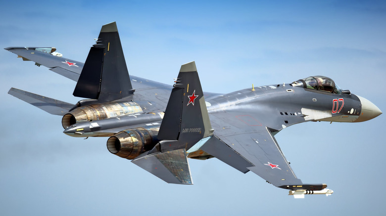A Russian Su-35 fighter jet flying over lightly cloudy skies