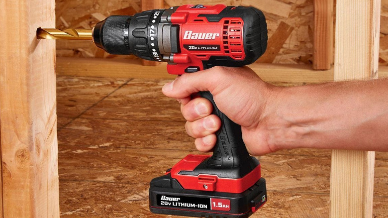 A Bauer drill/driver drilling into a wooden wall stud.