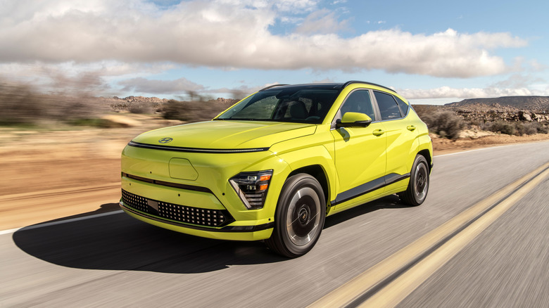 A green 2025 Hyundai Kona Electric driving on a desert road