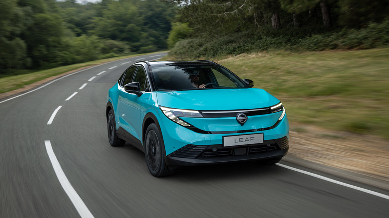 A blue 2026 Nissan LEAF driving on a forested road
