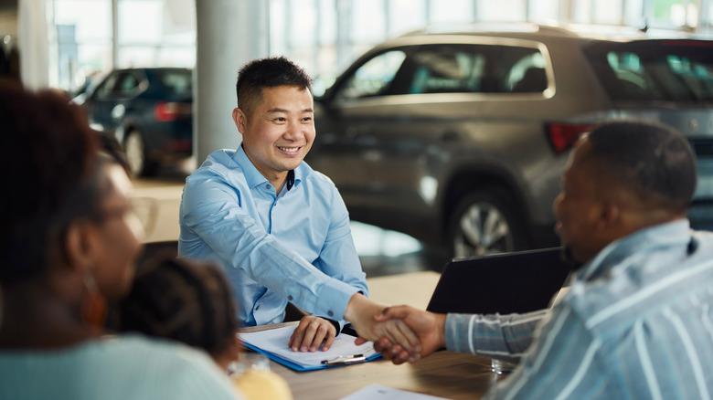 Car salesman shaking someone's hand