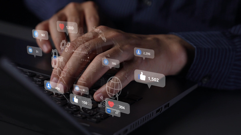 A person's hands typing on a keyboard in the dark with icons floating around it.