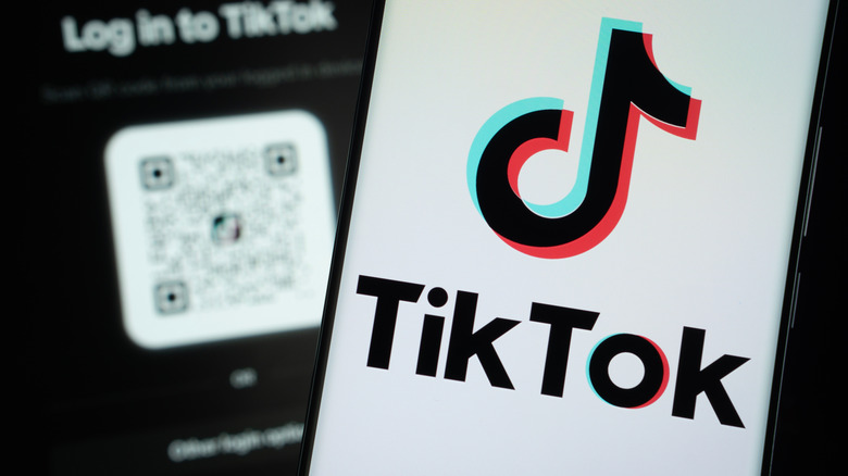 The TikTok displayed on a smartphone screen, another phone is visible in the background.