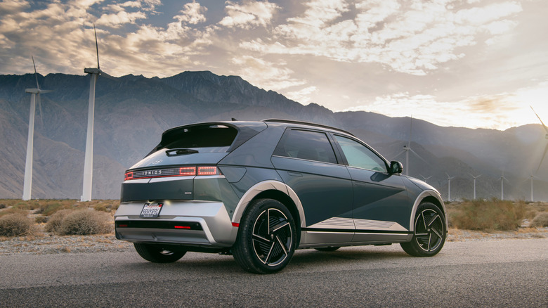 The 2025 Hyundai Ioniq 5 Limited parked on the road near several modern windmills and mountains