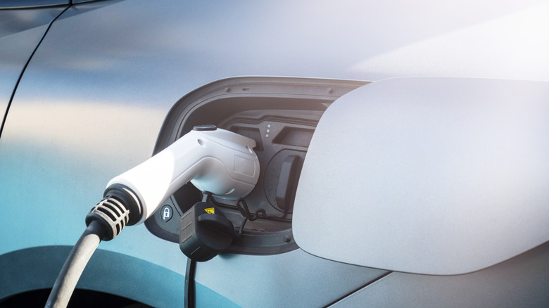 Close-up of a light-colored electric vehicle plugged into a charging cable