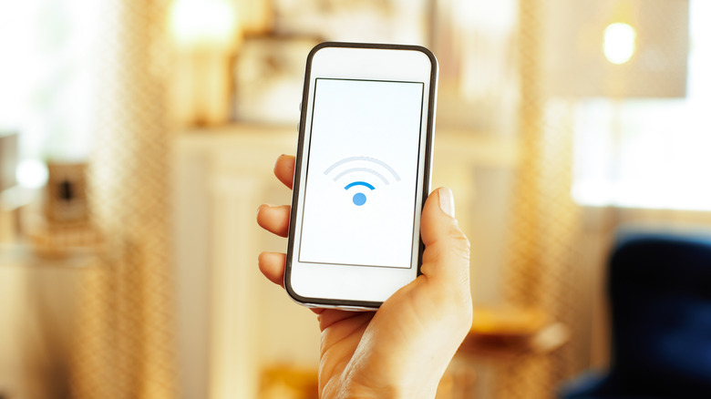 A person's hand holding a smartphone showing an image of poor Wi-Fi connection