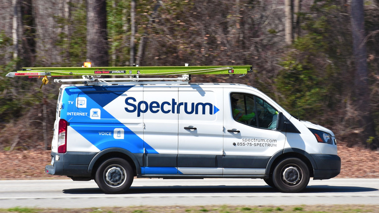 A Spectrum van driving down a road near a forest