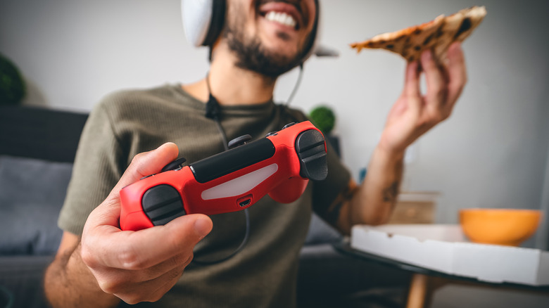 Man eating pizza with a wired gaming headset