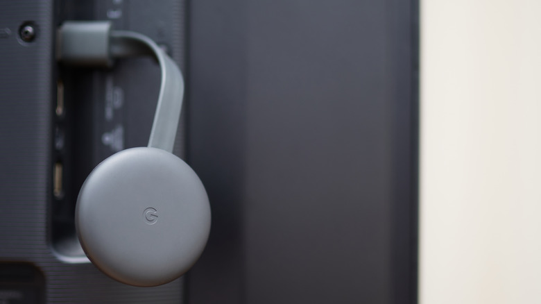 Google Chromecast plugged into rear of a TV set.