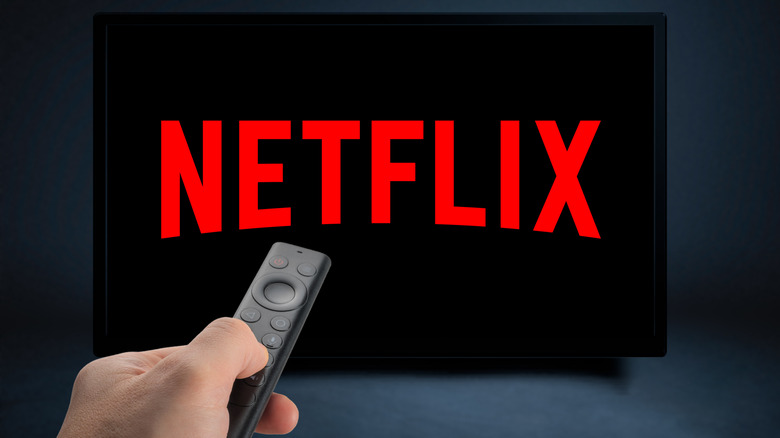 Person pointing NVIDIA SHIELD remote at TV showing Netflix logo.