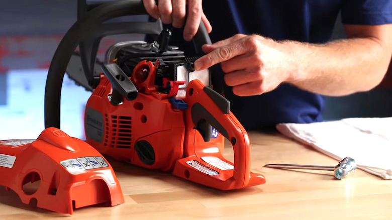Person pointing to the air filter on a Husqvarna chainsaw