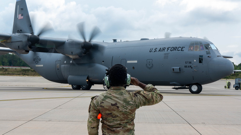 An aviator salutes a C-130J Super Hercules.
