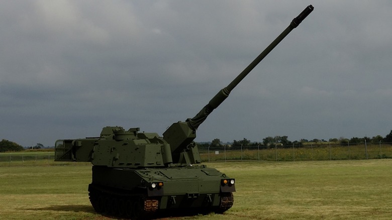 An M109-52 Self-Propelled Howitzer on a grassy field with its cannon pointed at a 45-degree angle