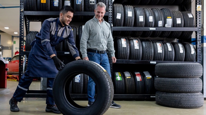 mechanic rolling tire for customer