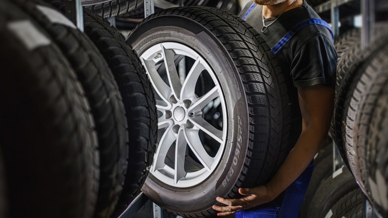 mechanic holding wheel in tire shop 