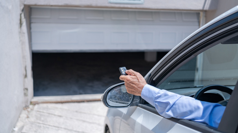 Man In Car Using Remote Control To Open The Automatic Garage Door
