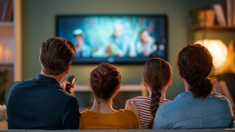 A family watching TV on a sofa, the TV is out of focus.
