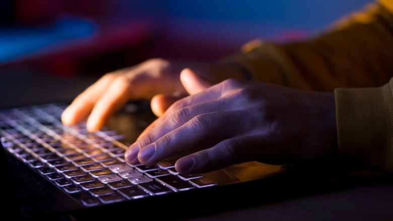 man's hands on lit laptop keyboard