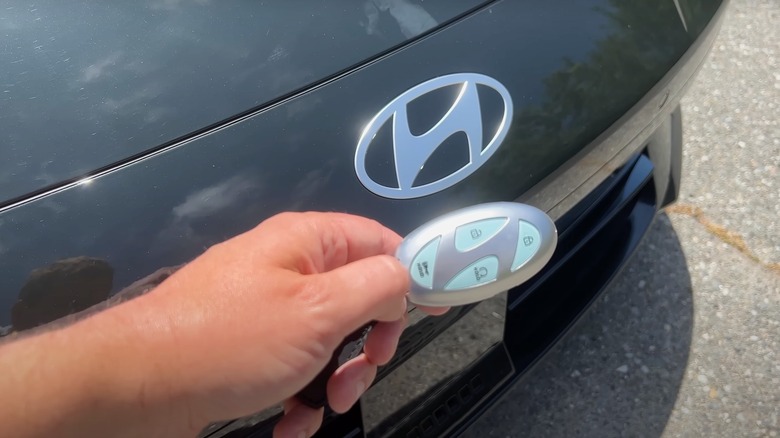 A person holding the Hyundai logo key next to an Ioniq 6