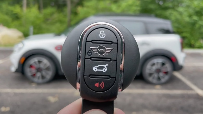 A person holding the circular Mini key fob next to a Countryman