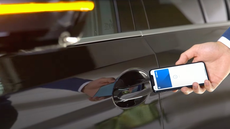 A person using their phone to unlock their BMW