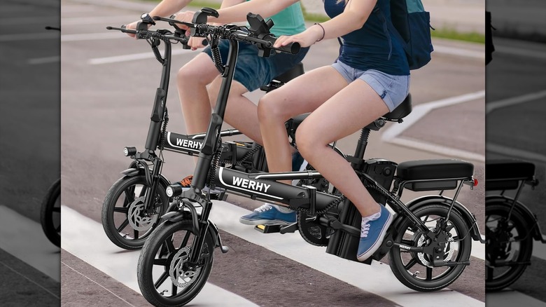 A woman riding an e-bike with a dog in a crate on the front.