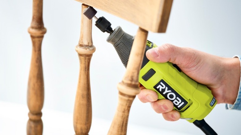 Person using Ryobi rotary tool to sand chair