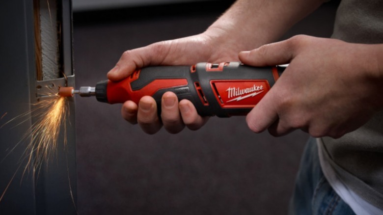 Person using Milwaukee rotary tool to grind metal