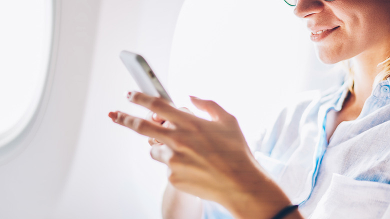woman reading phone inside plane