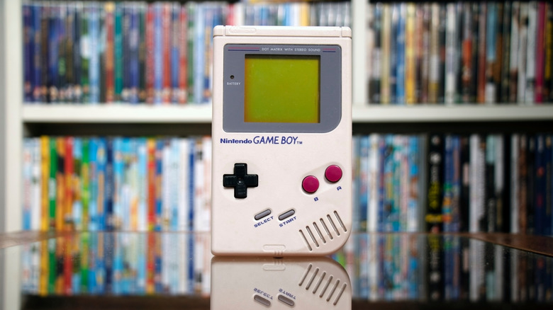 A Game Boy with video games in the background.