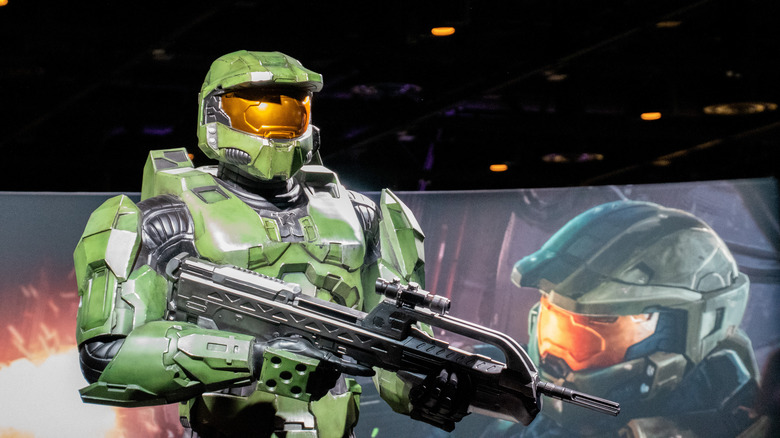 Halo's Masterchief model poses in front of his poster.