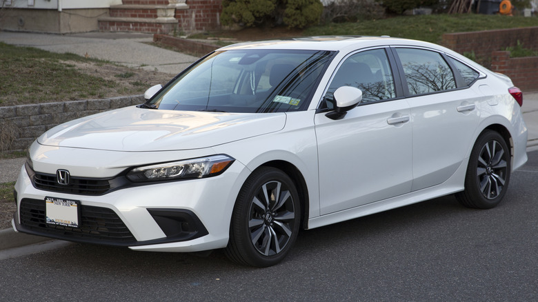Platinum white pearl 2022 Honda Civic Sedan EX parked on roadside net to a buildling