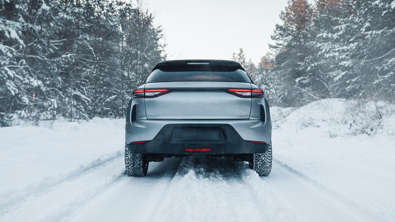 A rear view of an SUV driving on snow-covered road.