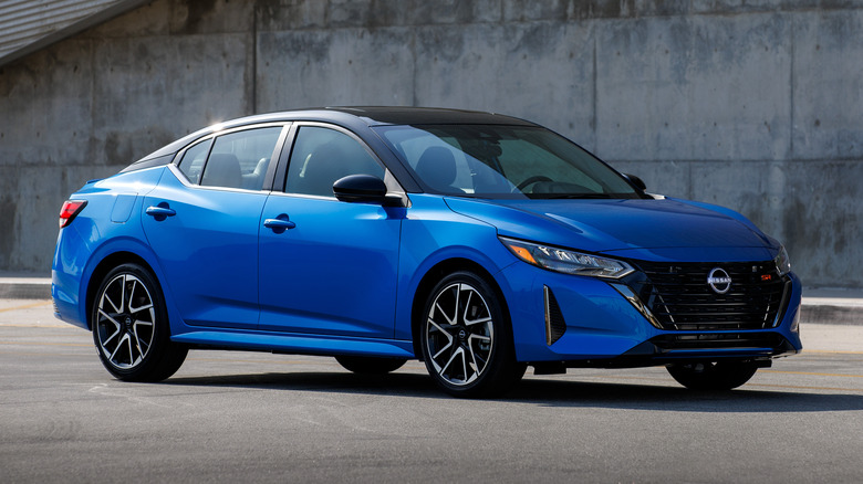 Blue Nissan Sentra parked in front of a concrete wall