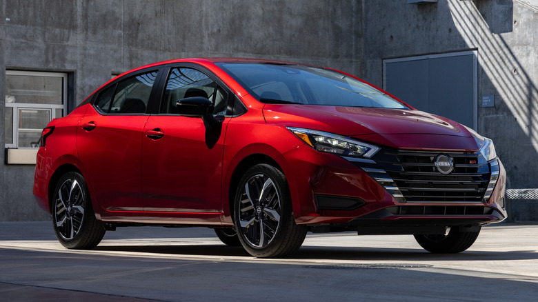 Red Nissan Versa parked in front of a concrete building