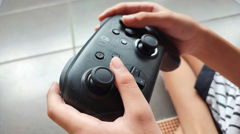 Person holding a Nintendo Switch Pro controller.