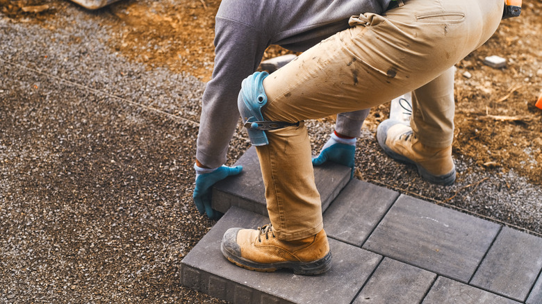 man lays pavers on patio