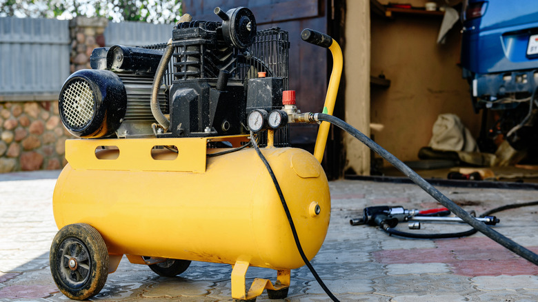 Air compressor for car repair on the background of garage.